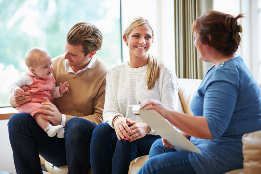 A family social worker meets with a couple and infant.