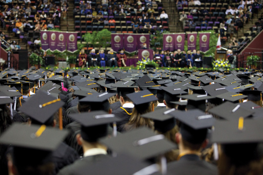 A group of students wearing caps and gowns in a graduation ceremony.