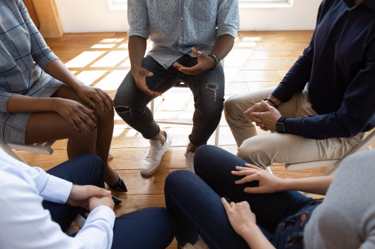 Clients sit in a circle in a group therapy session.