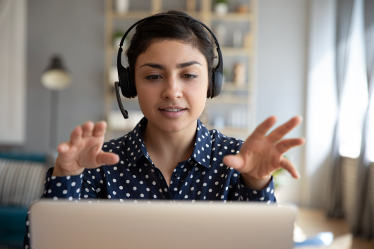 A social worker wearing a headset works with a client via computer.